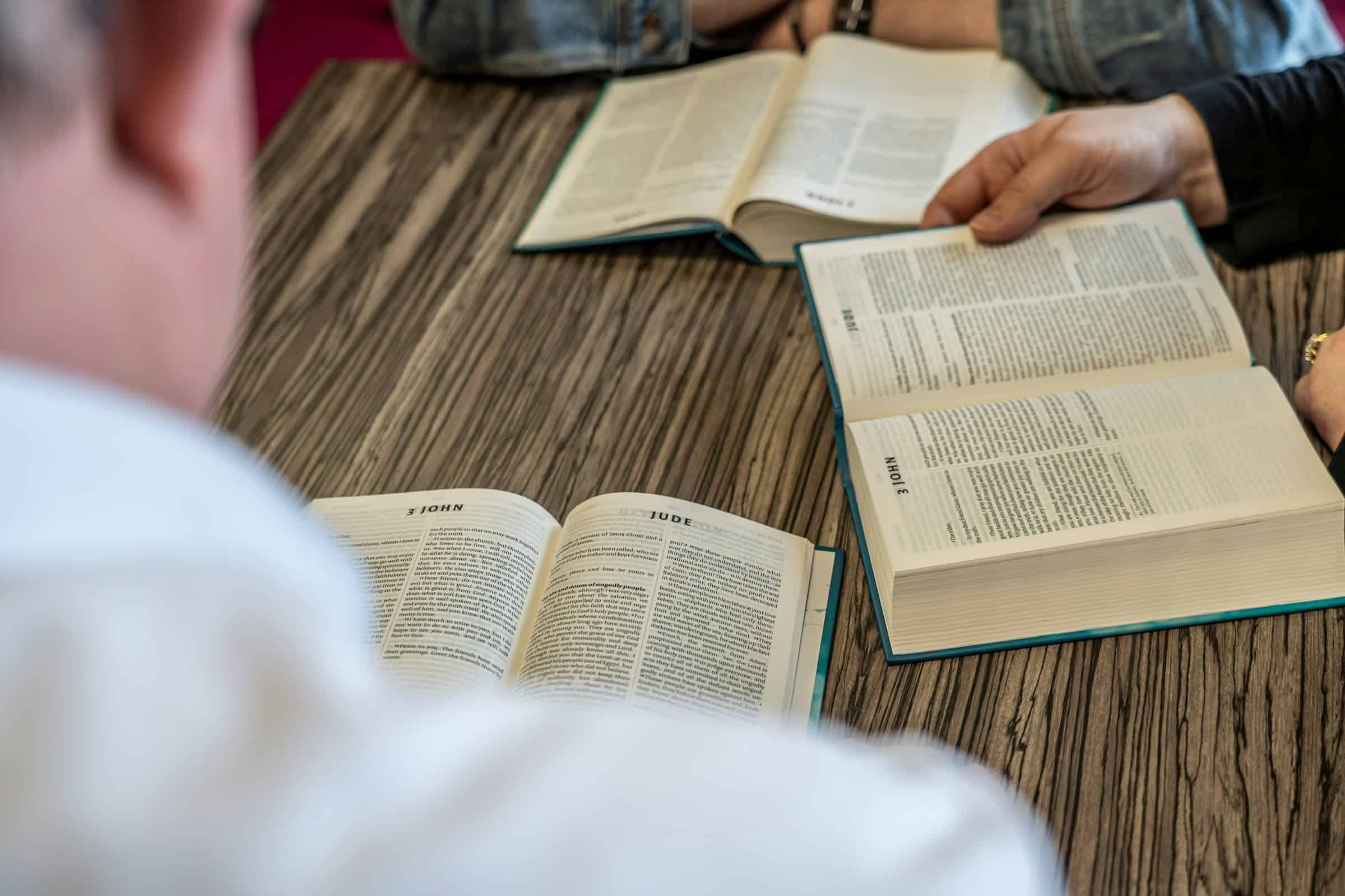 two people sitting at a table with open books